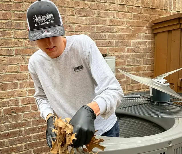 Clearing debris from an HVAC unit during routine maintenance.